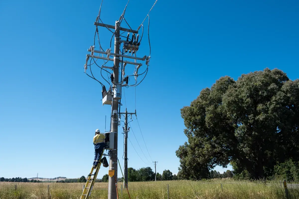 Technician installing a recloser controller on a rural distribution pole